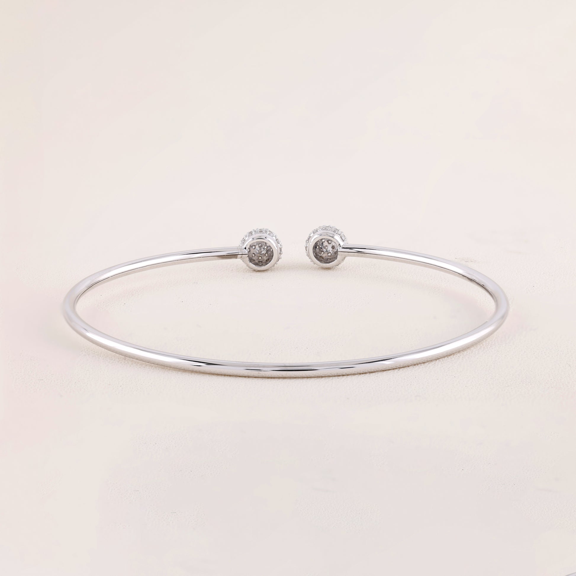 Silver bracelet with two round silver charms on a light pink background