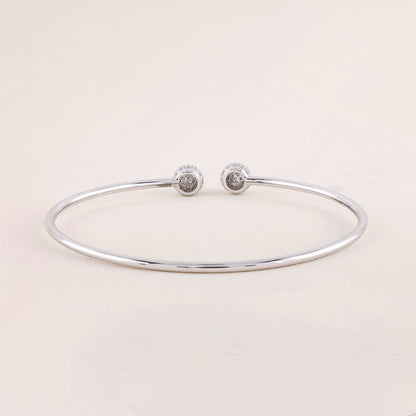 Silver bracelet with two round silver charms on a light pink background