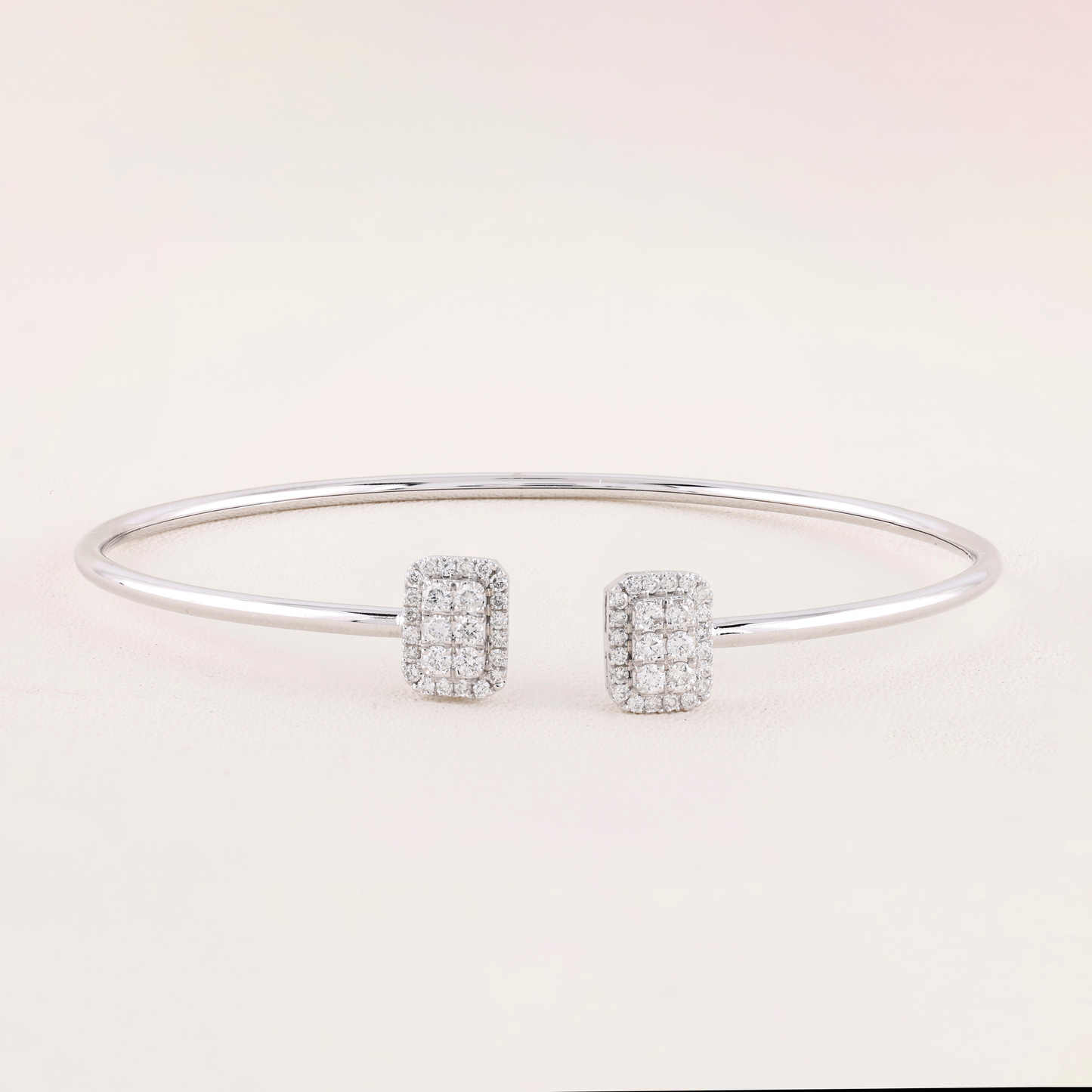 Silver bracelet and earrings on a light pink background