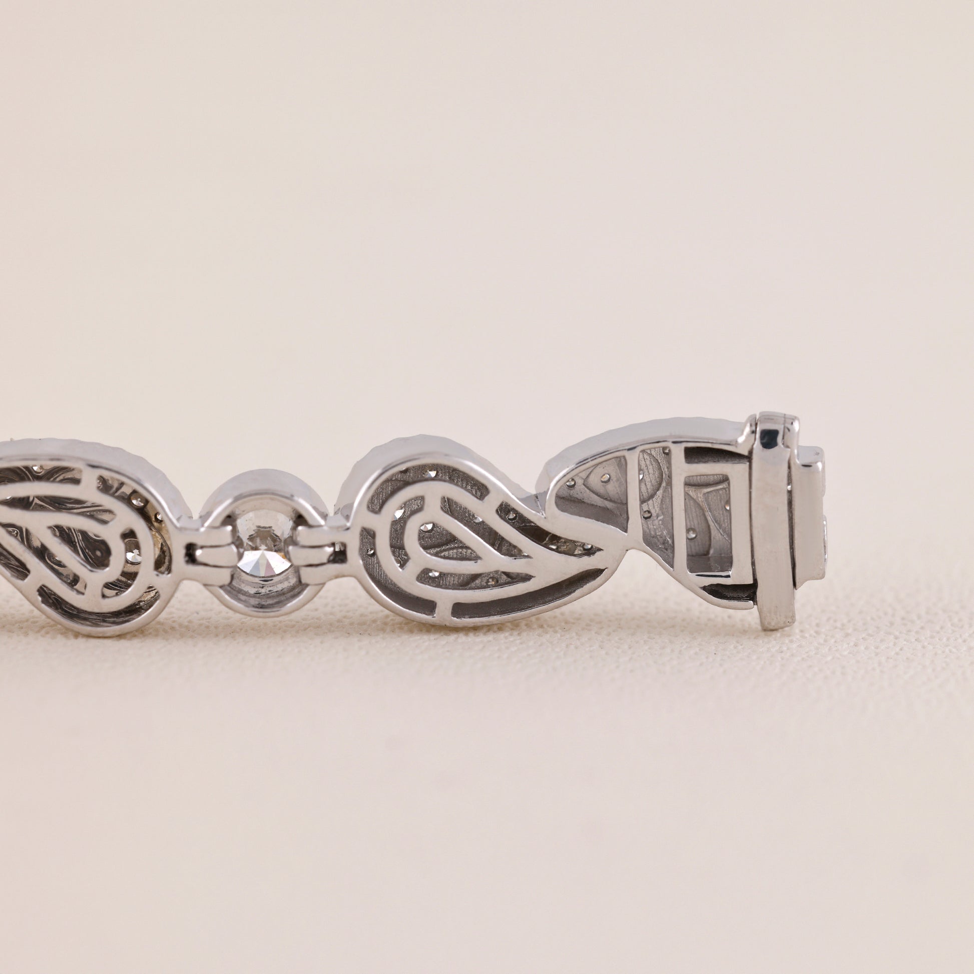 Silver bracelet with intricate design on a light beige background