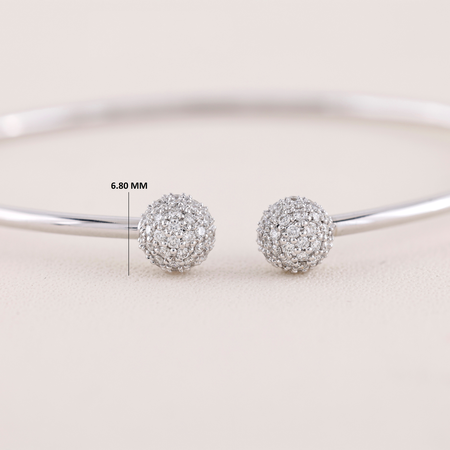 Silver ball earrings with a measurement label on a light background