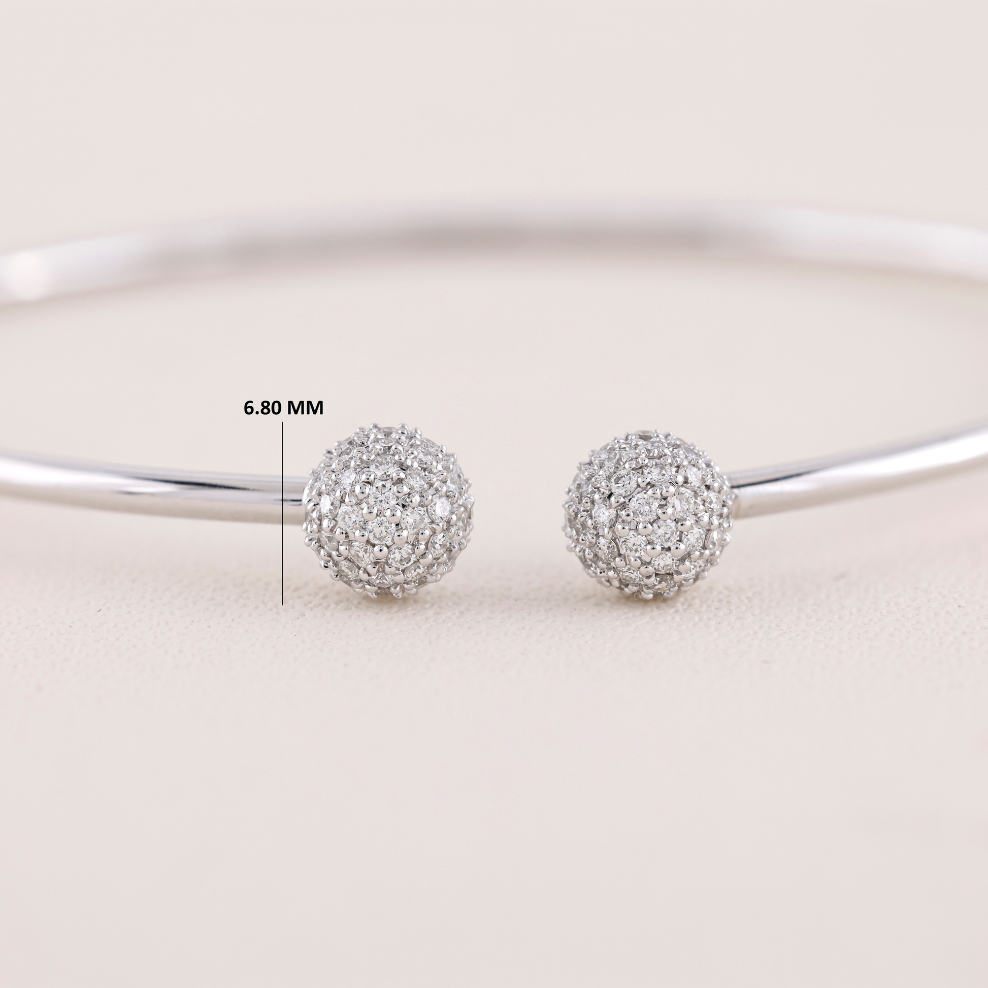 Silver ball earrings with a measurement label on a light background