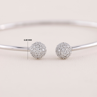 Silver ball earrings with a measurement label on a light background