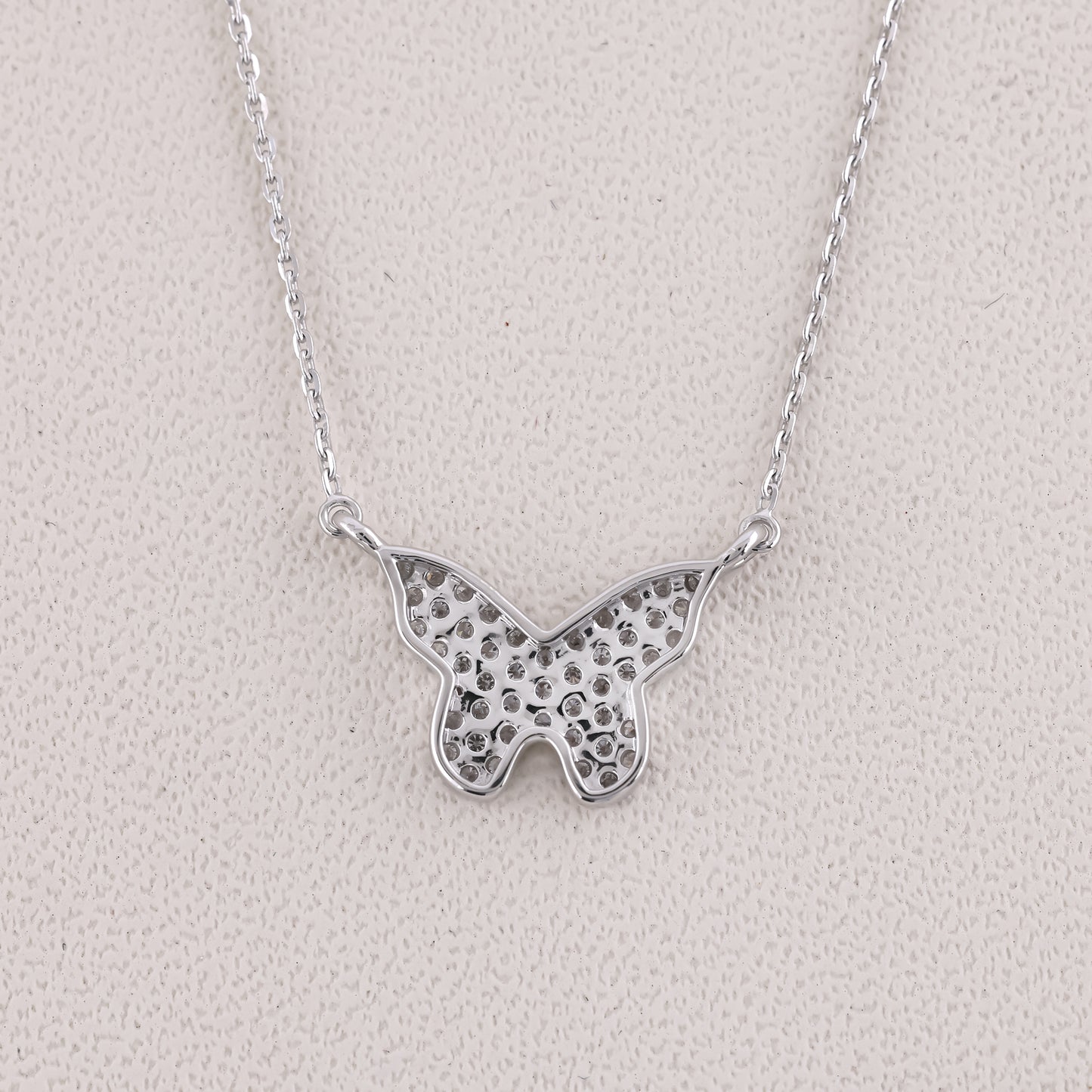 Silver butterfly necklace on a light gray background