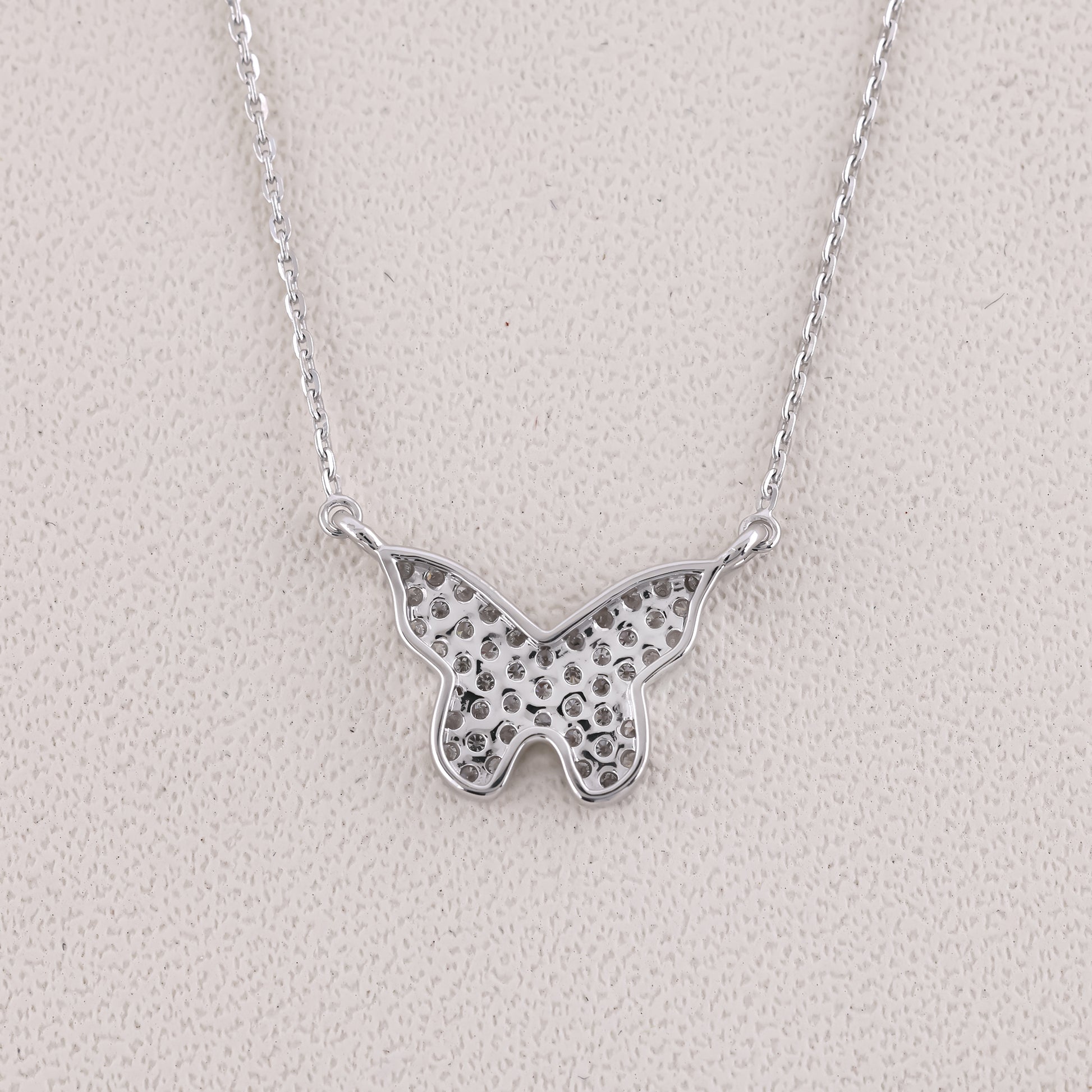 Silver butterfly necklace on a light gray background