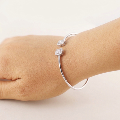 Silver bracelet with two diamond-like beads on a wrist against a white background