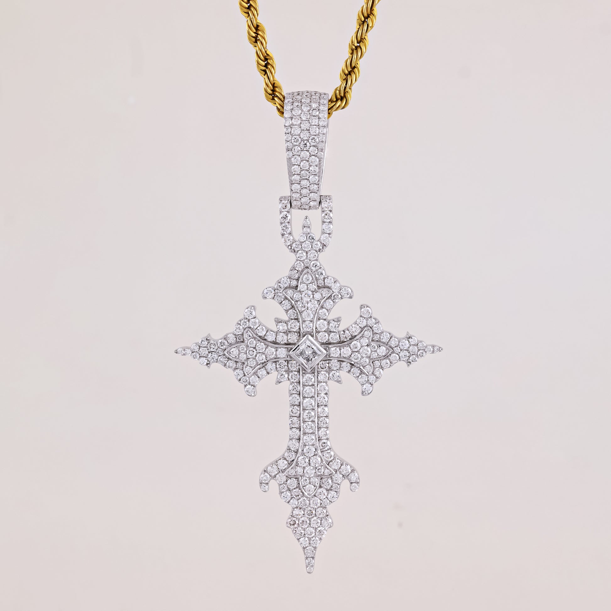 Diamond-studded cross pendant on a gold chain against a light gray background