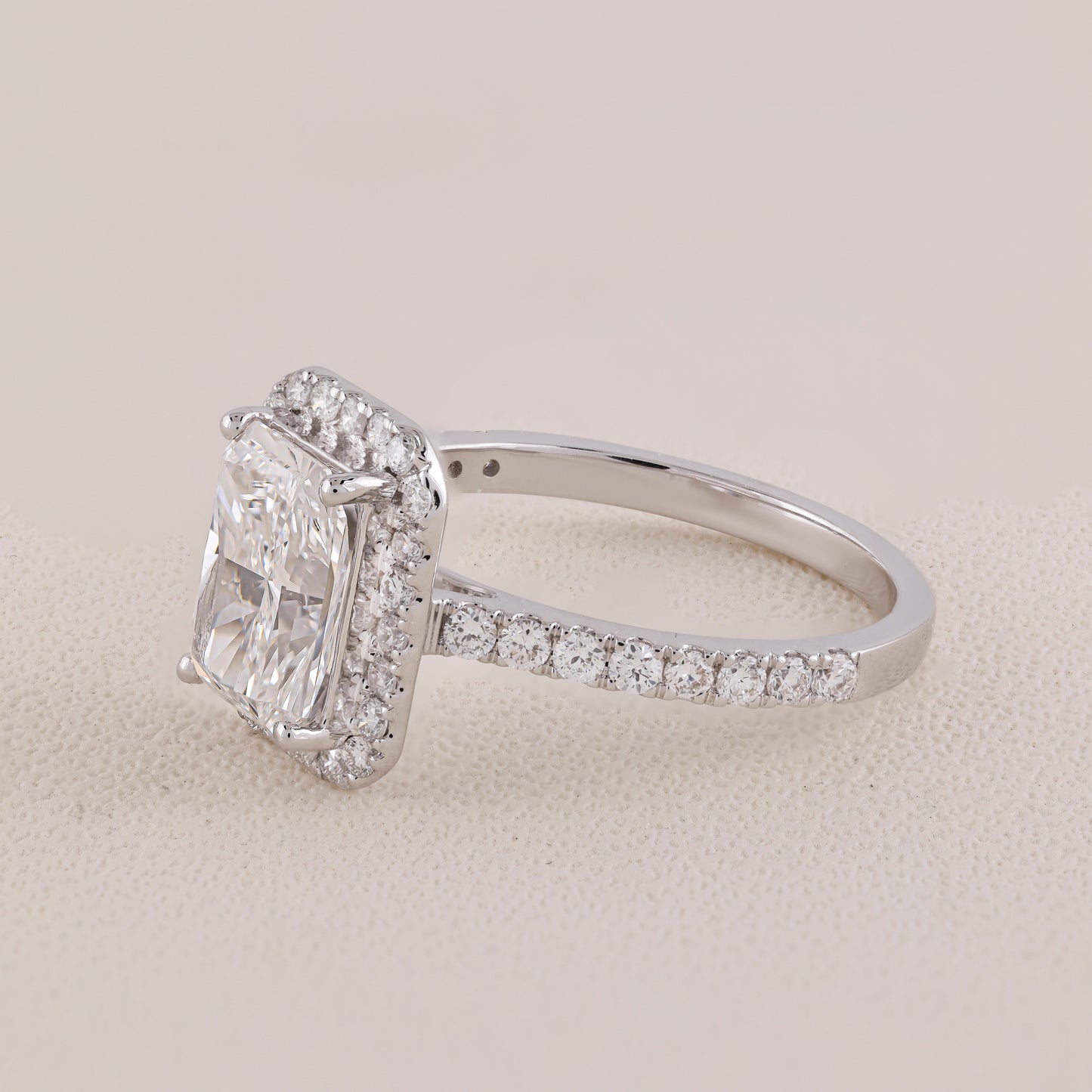 Diamond ring with a rectangular center stone and smaller stones on a light background