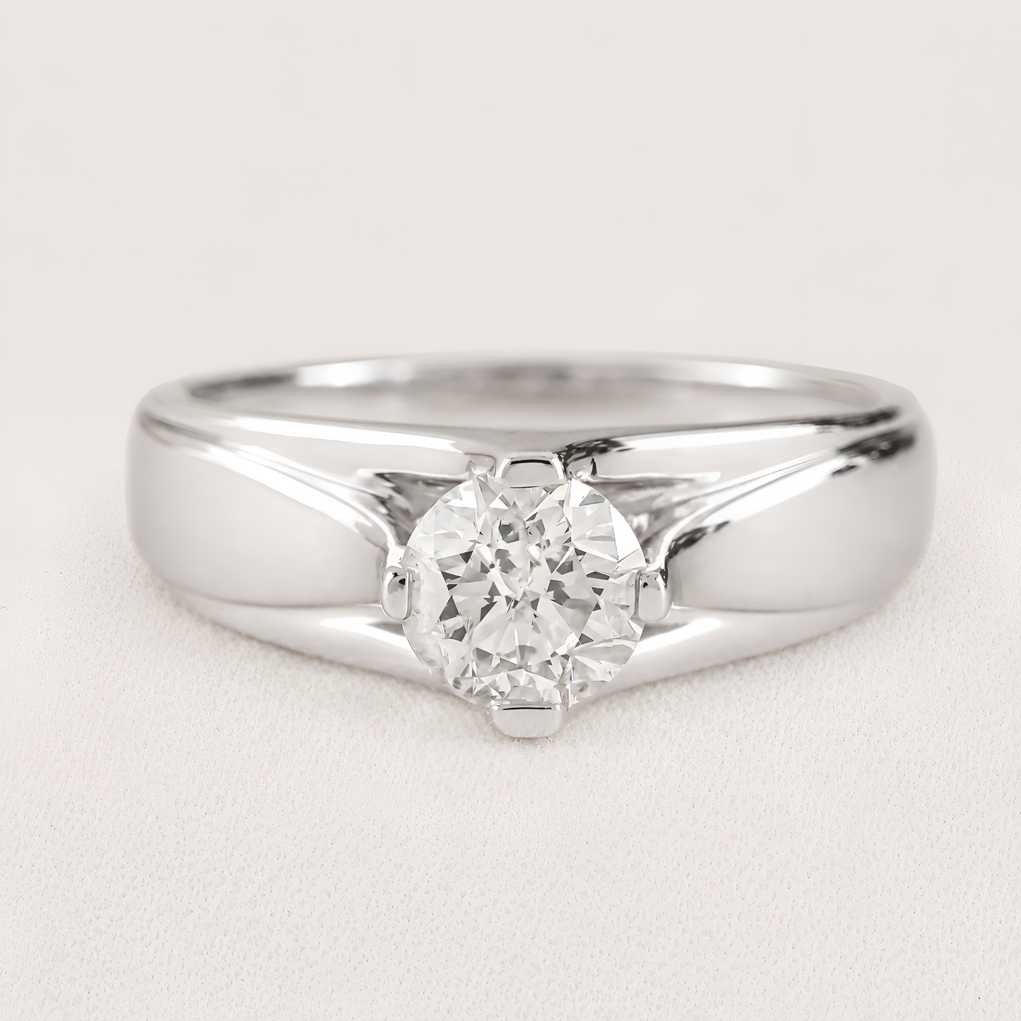 A classic solitaire engagement ring featuring a round brilliant-cut diamond set in a polished silver-colored metal band, shown on a light textured background.