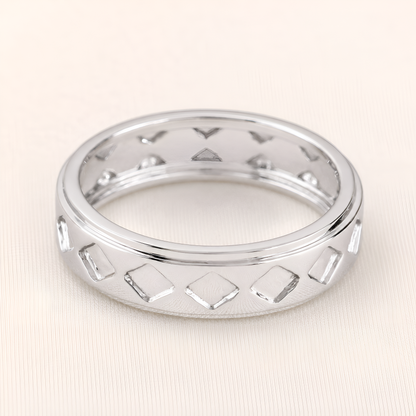 A silver band ring featuring a repeating pattern of open diamond-shaped cutouts, shown on a light beige textured background.