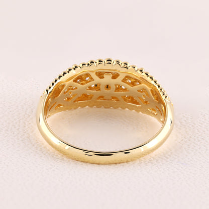 Gold ring with intricate design on a light pink background