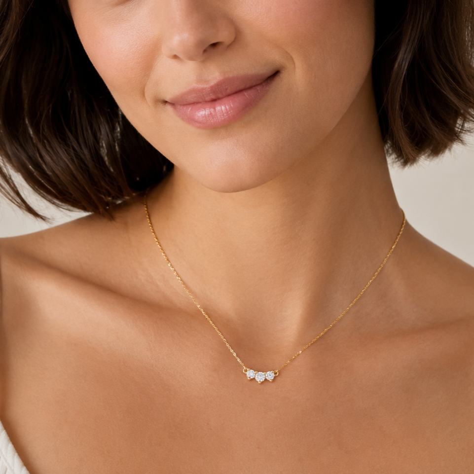 Close-up of a woman wearing a gold necklace with a small pendant.