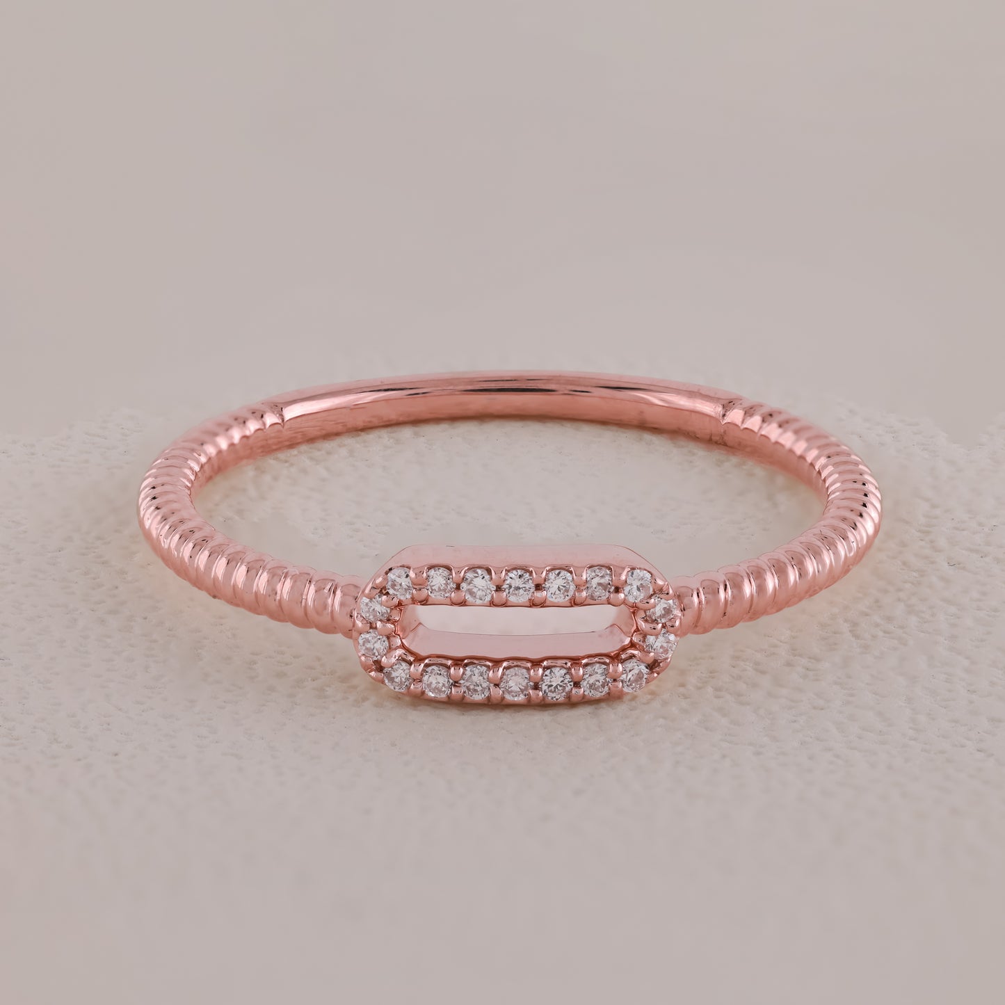 Rose gold ring with diamond accents on a light beige background