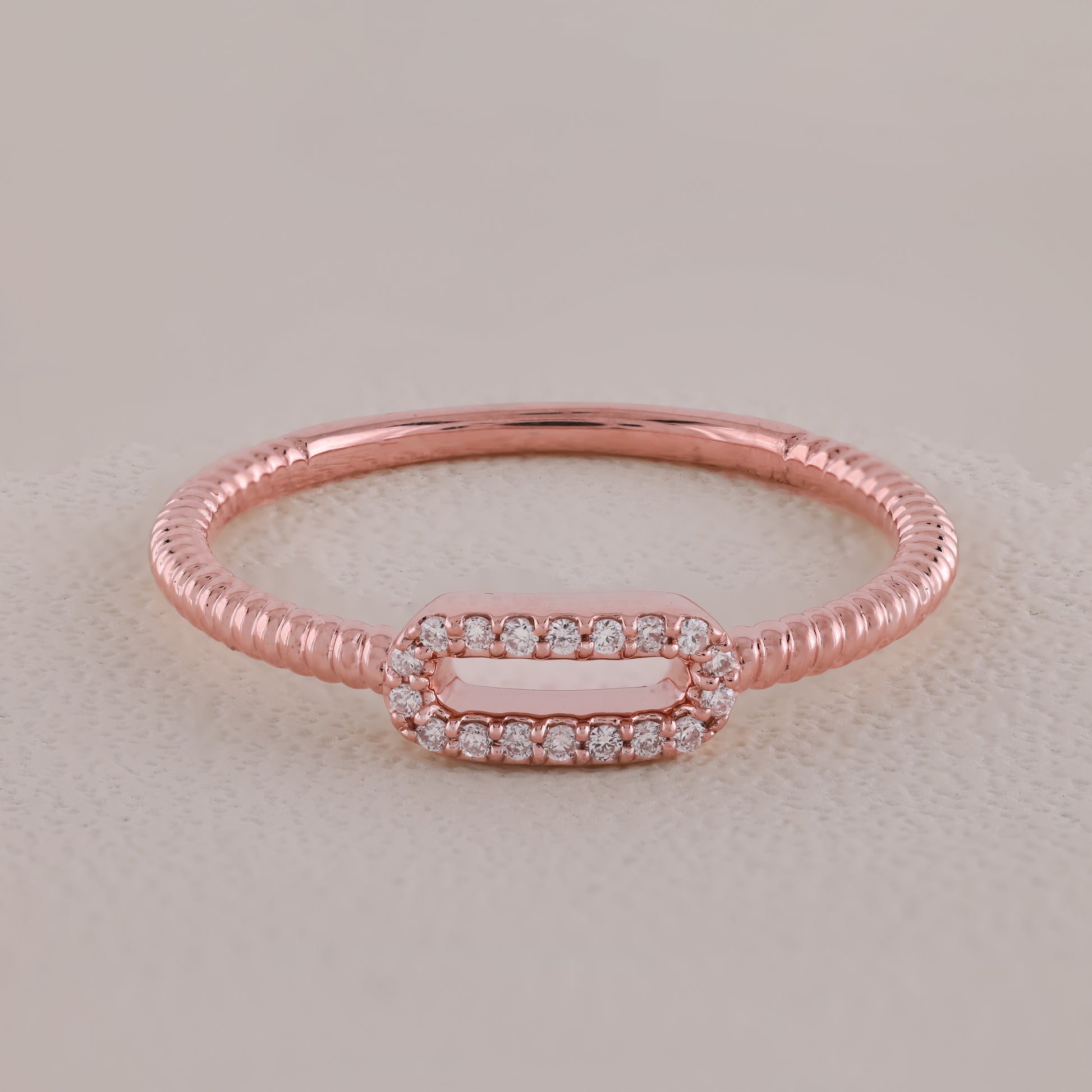 Rose gold ring with diamond accents on a light beige background
