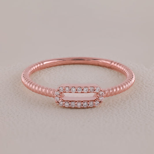 Rose gold ring with diamond accents on a light beige background