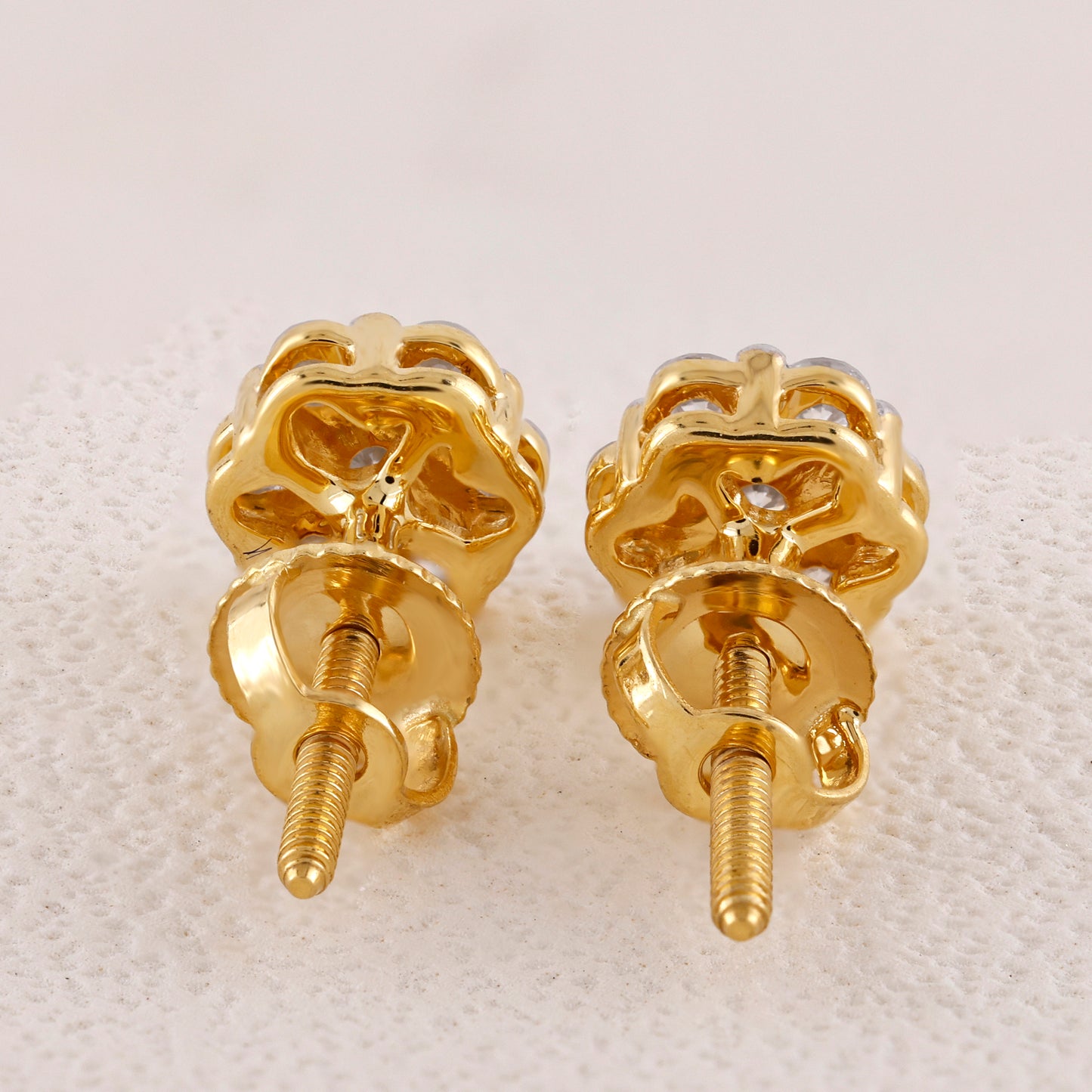 Pair of gold screw-back earrings on a textured white background